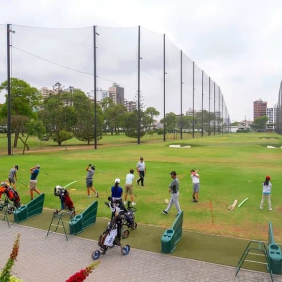 Golfers on a driving range with perimeter netting